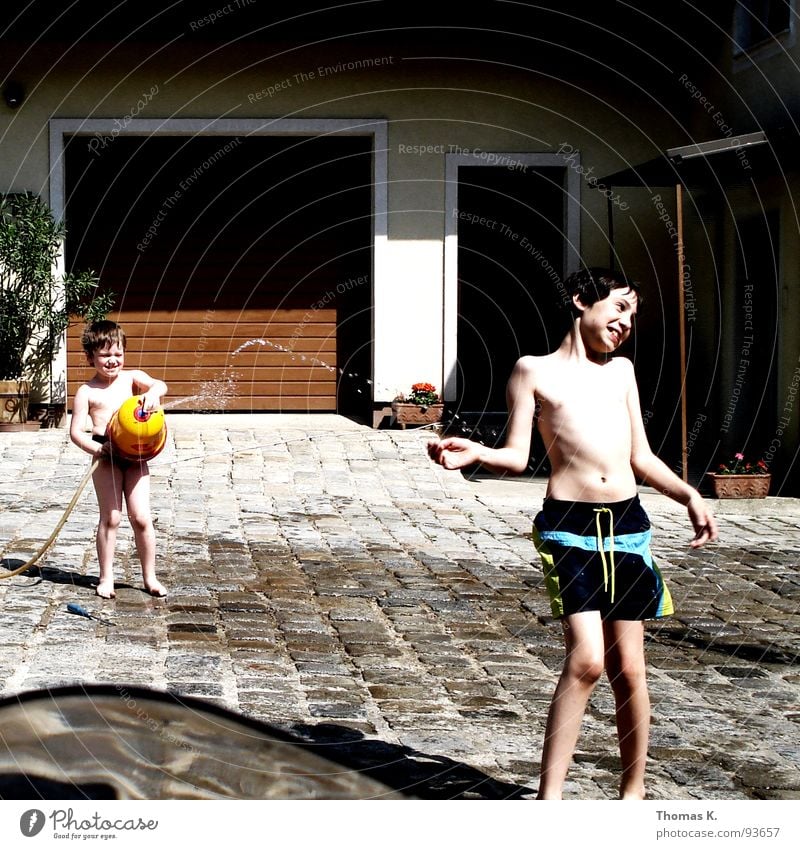 Gotcha! Child Summer Sun Vacation & Travel Garage door Cold Wet Playing Hose Swimming trunks Romp Water fountain Farm Cobblestones fresh Refreshment